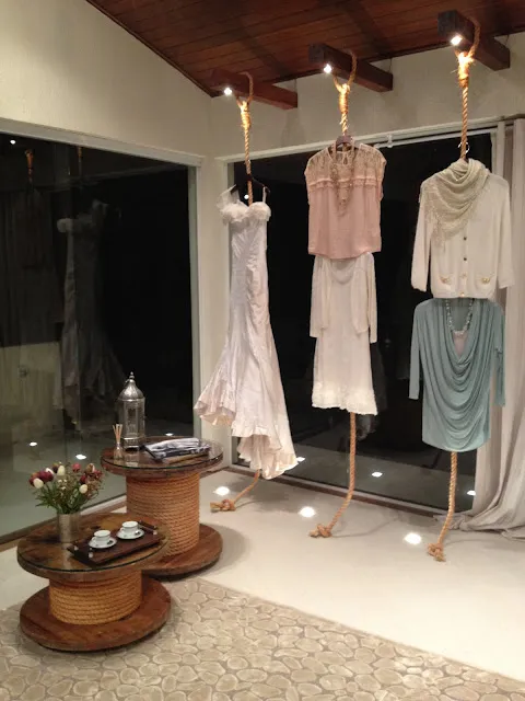 Interior do ateliê de Adriana, com vestidos pendurados em cordas e poltronas estampadas